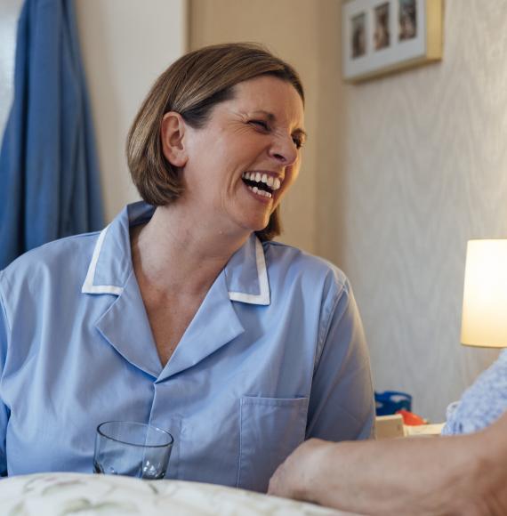 Nurse sat next to an older woman's bed