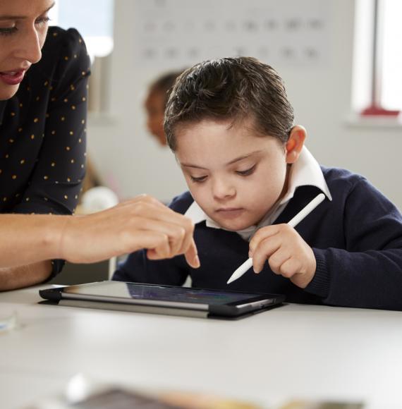 Young female teacher working with a Down syndrome schoolboy