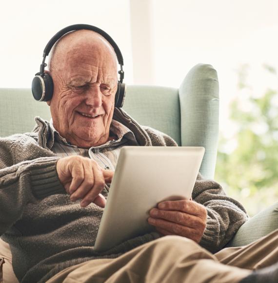 Happy elderly man at home using digital tablet