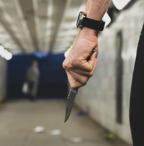 Person in an underpass holding a knife