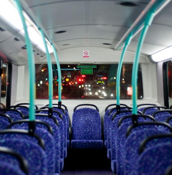 Rows of empty blue seats on a London Double Decker Bus at night