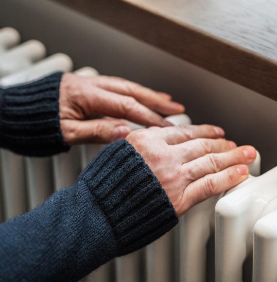 A man tries to warm his hands on a radiator