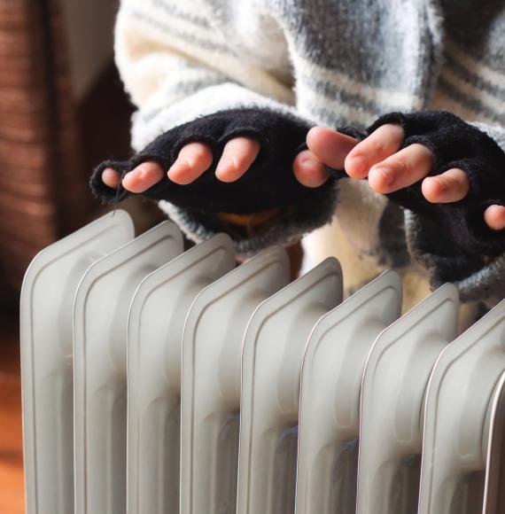 Woman heating her hands in her cold home