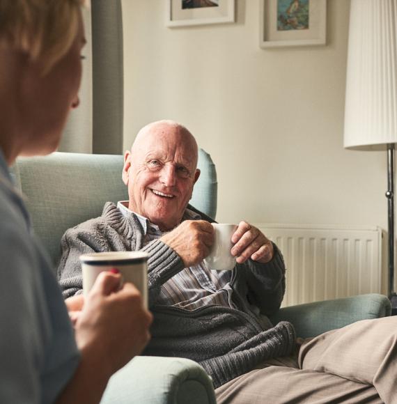 Smiling senior man talking to female caregiver