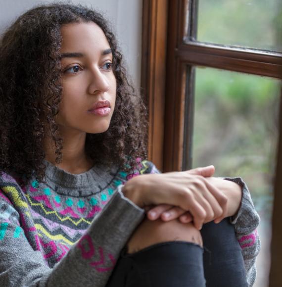 Vulnerable child sitting by window