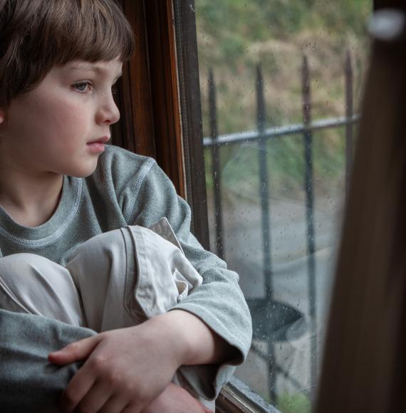 Young boy looking out of window