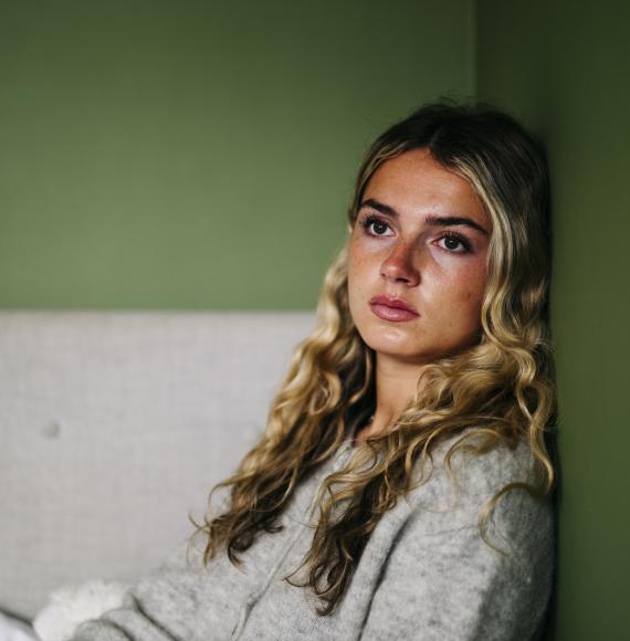 A teenage girl sat on the floor looking upset